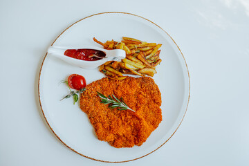  Viennese Schnitzel with fried potatoes, rosemary and ketchup on white plate.