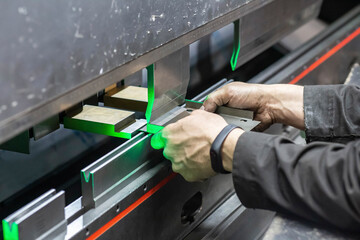 Worker holds a part in a CNC bending machine