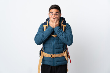 Young mountaineer man with a big backpack isolated on white background with surprise facial...