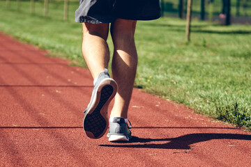 Athletic young man running. Exercising, stretching in urban area or park in the morning. Self care authentic, wellness and sport concepts