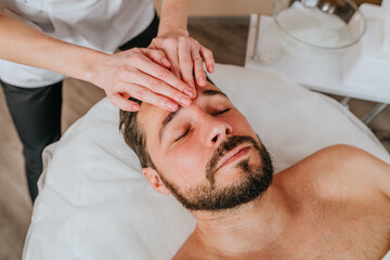 Obraz na płótnie Canvas Esthetician or facialist gives a relaxing facial massage to a man