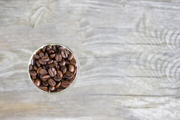 Coffee grains, glass goblet with coffee grains on wooden background, top view. Roasted coffee beans flat lay
