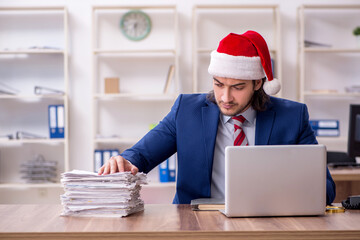 Young male employee working in the office at Christmas Eve