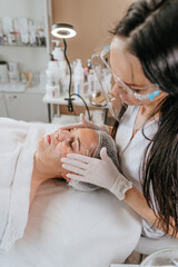 Esthetician or facialist making facial cleansing procedure