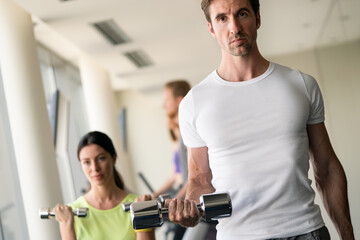 Sport, fitness, lifestyle and people concept. Group of happy poeple with dumbbells in gym