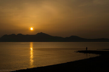 Obraz premium Winter Sunrise Morning behind Mountains with man fishing - Amanecer en Bahia de Pollensa con un Sr. Pescando
