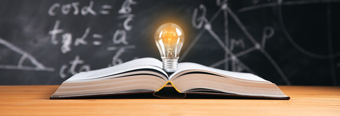 the light bulb on book with blackboard background