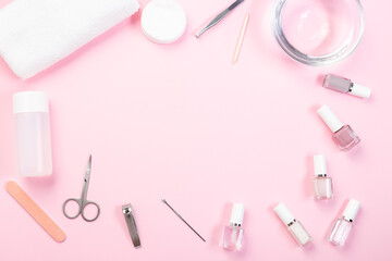 Frame with spa equipment, manicure or pedicure set, nail coat or polish, towel and water, on pink background, horizontal, copy space