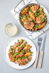 Chicken stew with potatoes, mushrooms and green peas, on white plate and in a metal pot, top view, vertical