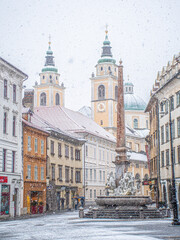 Fototapeta na wymiar Ljubljana Town Square with Ljubljana cathedral and three bridges fountain during snowfall, Central Slovenia Region
