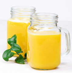 Orange juice and green leaves on a white background.A glass of orange juice Healthy food. Vegan food