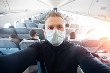 Fototapeta na wymiar Portrait of tourist man in medical mask in airplane, concept travel trip in covid
