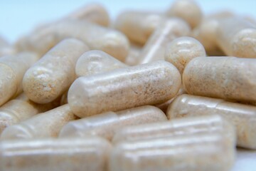 Beige oval pills, tablets. Medicines on the white background. Pile of pills, capsules. Addiction to drugs and supplements. Medical and healthcare concept. 