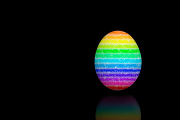 Easter egg painted with different rainbow colors, isolated on black bakcground.