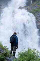 Man hiker exploring a mountain waterfall