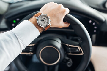 Closeup of a hand on steering wheel and speedometer in the background