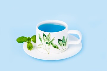 Porcelain cup of organic blue butterfly pea flower tea with mint leaf