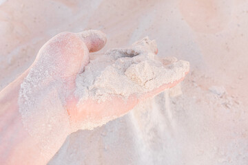 The guy's hand takes or touches the white beach sand close up
