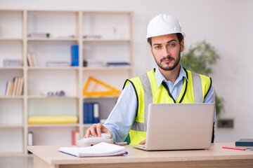 Young arm injured male architect working in the office