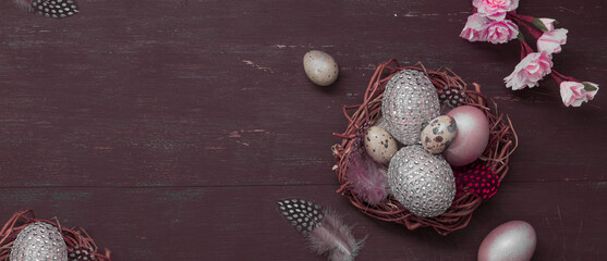 Happy Easter Flat lay nest and eggs on brown bakcground with pink blossom flowers. Greeting Happy Easter banner copy space