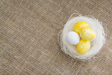 Flat lay nest and eggs on burlap fabric bakcground. Easter greeting card template