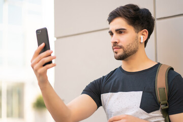 Young man using face id for unlock mobile phone outdoors.