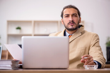 Ill cigarette addicted male employee working in the office