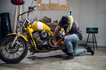 Fototapeta na wymiar A young mechanic tuning a motorcycle in an auto repair shop. Hobbies and work activity