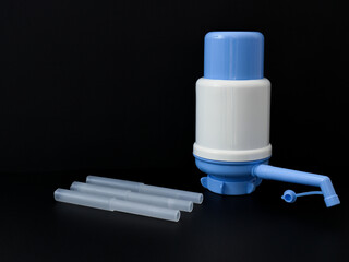 blue color classic manual carboy demijhon water pump and interlocking transparent plastic pipe on black background