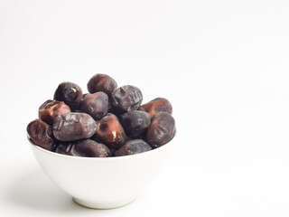 Selective focus image a bunch of fresh raw dates in a bowl isolated on white background with copy space.