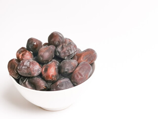 Selective focus image a bunch of fresh raw dates in a bowl isolated on white background with copy space.