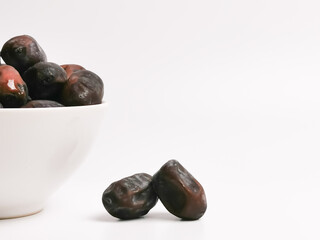 Selective focus image a bunch of fresh raw dates in a bowl isolated on white background with copy space.