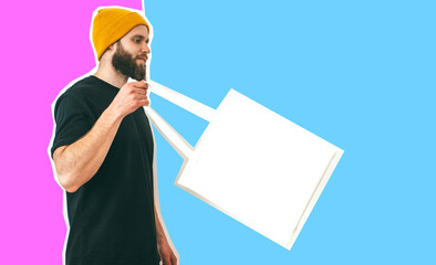 Young man is holding white textile eco bag on color background. Mockup for design