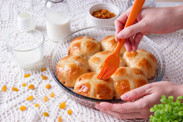 Freshly baked Easter buns, pastry chef greases buns with glaze.