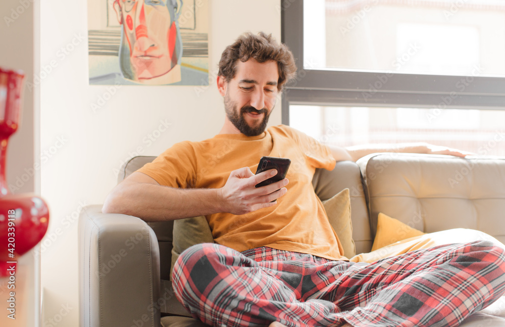 Sticker young bearded man on a couch with a smart phone