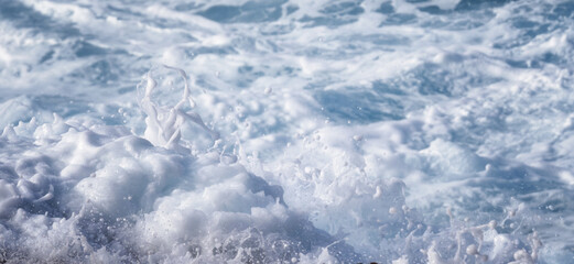 wave breaking on the rocks with bubbles and white foam 