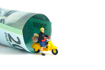Miniature people toys conceptual photography. COD (Cash on delivery) service. Postman courier with cash money paper, isolated white background.
