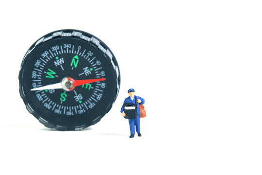 Miniature people toys conceptual photography. Address navigation. Postman courier with a compass, isolated on blue background.