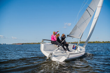 A beautiful white yacht is sailing in the wind on the river against the background of a beautiful...