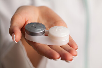 Close up of woman holding container with contact lenses