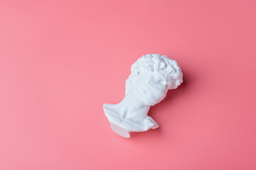 Head statue in medical mask on pastel pink background, health concept 