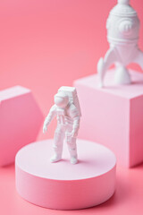 Astronaut figurine on the podium on a pink background. International Day of Human Space Flight concept