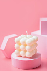 A trendy soy cube bubble candle on a pink podium at the pink background