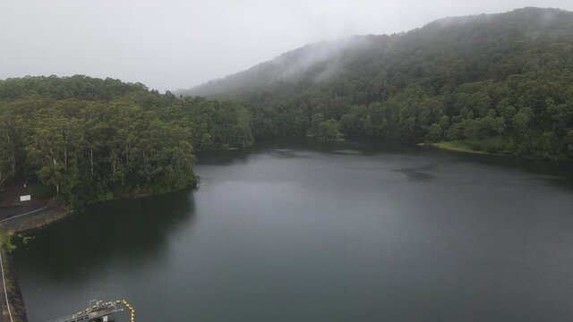 Impound Water At Reservoir - Karangi Dam On A Foggy Day With Dense Mountain Forest In NSW, Australia. - aerial