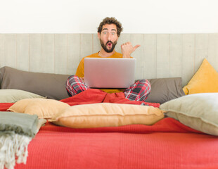 young bearded man looking astonished in disbelief, pointing at object on the side and saying wow,...