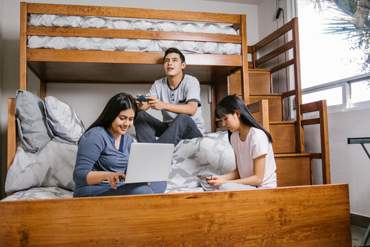latin siblings with laptop in bed at home