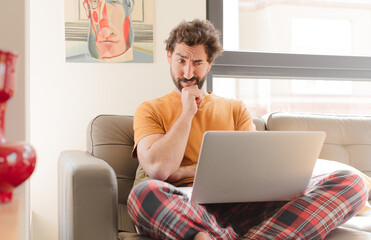 young bearded man thinking, feeling doubtful and confused, with different options, wondering which...