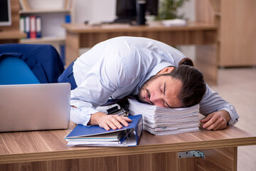 Fototapeta premium Young businessman employee unhappy with excessive work in the of