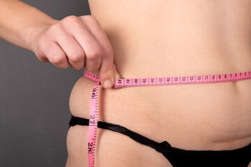 overweight, a girl measures her waist with a centimeter