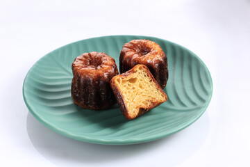 Canele Classic French Pastry Bordeaux on Green Plate, Isolated White Background